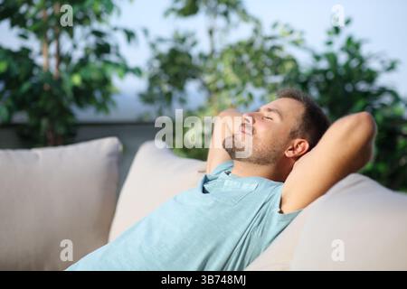 Man relaxing sitting on a couch in a terrace a sunny day Stock Photo