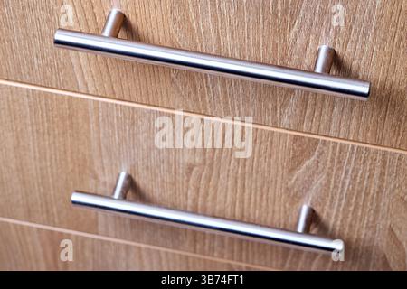 Rectangle shaped kitchen cabinet with stainless steel brushed handles close up selective focus shot. Cabinet door adorned with metal handles Stock Photo