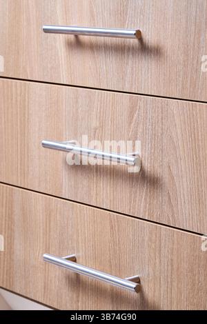 Rectangle shaped kitchen cabinet with stainless steel brushed handles close up selective focus shot. Cabinet door adorned with metal handles Stock Photo