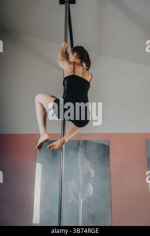 Woman Performing Pole Dance in a Fitness Studio with Dramatic Lighting Stock Photo
