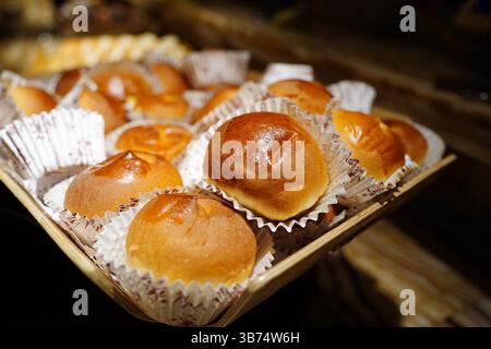 Freshly baked round buns in a basket on a wooden table. Stock Photo