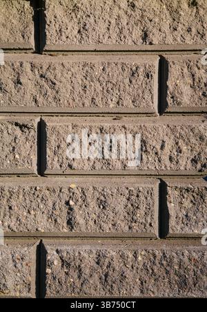 Gray brick wall texture lit by warm sunlight. Urban background with natural lighting Stock Photo