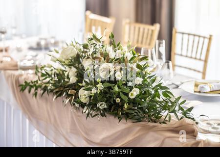 Beautiful floral decoration on the wedding table, which is prepared for the newlyweds. A wedding table covered with a white tablecloth, decorated with Stock Photo