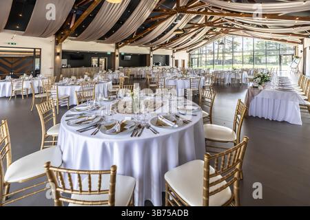 Wedding setting and decorated tables in a beautiful modern interior of a performance hall with a modern light ceiling of wooden construction. Stock Photo