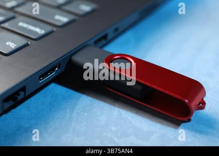 Usb flash drive connected to laptop on blue textured table, closeup Stock Photo