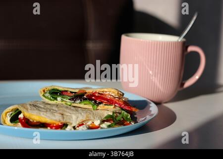 Fresh omelet tortilla wrap filled with cream cheese, smoked salmon, avocado, spinach, and veggies. A colorful, trendy and healthy breakfast Stock Photo