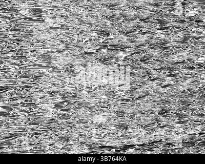 Shiny crumpled metal foil texture with reflective metallic surface, an abstract patterns of light and shadow. Stock Photo