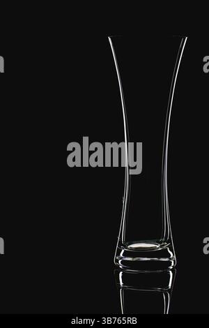 Glass vase, isolated on the black background. Empty glass vase with reflection on black glass table Stock Photo