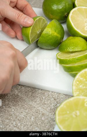 The process of slicing fresh lime fruit with a kitchen knife Stock Photo
