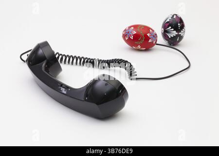 Old phone reciever and cord connection with Easter eggs. Easter hotline concept Stock Photo