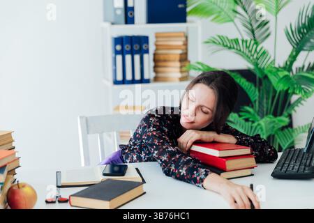 Woman in business suit fell asleep at desk in office tired Stock Photo