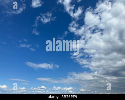 Blue sky with scattered fluffy white clouds and a touch of gray clouds. Stock Photo