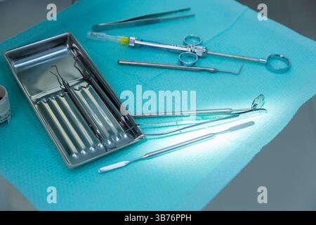 This image features an assortment of dental instruments neatly arranged on a light blue surface, showcasing essential tools for dental procedures in a Stock Photo