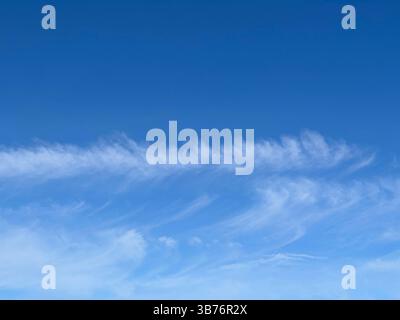 Vibrant blue sky with soft white clouds, creating a tranquil and beautiful scene. Stock Photo