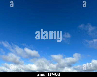 The deep blue sky is filled with fluffy white clouds on a beautiful day. Stock Photo