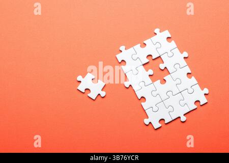 White puzzle with missing piece on bright orange background Stock Photo