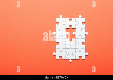 White Puzzle with Missing Piece on Orange Background Stock Photo