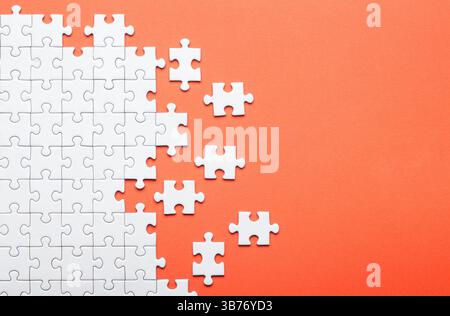 White Puzzle Pieces on Orange Background Representing Problem Solving Stock Photo