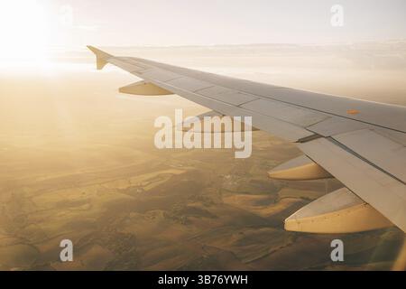 Sun shines brightly on the wing of the plane. View from the porthole to the ground. Stock Photo