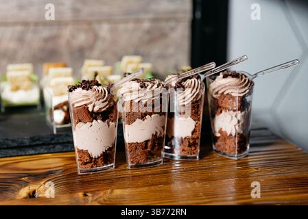 Individual dessert cups filled with layers of chocolate mousse and brownie chunks, topped with whipped cream and chocolate curls. Stock Photo