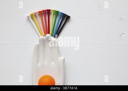 Detail of ceramic hand with golf balls and tees on the white wooden desk - Flat Lay Photography Stock Photo