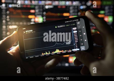 Venice, Italy - 06 April 2021: Businessman is checking Bitcoin price chart on digital exchange on mobile phone screen, cryptocurrency future price act Stock Photo