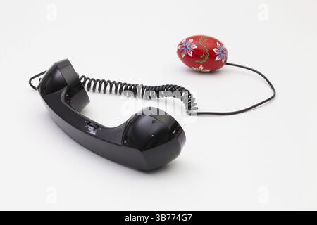 Old phone reciever and cord connection with Easter eggs. Easter hotline concept Stock Photo