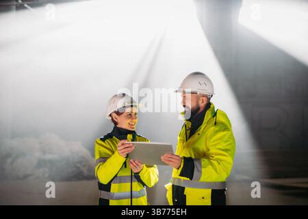 Engineers discussing construction plans using a tablet on site. Stock Photo