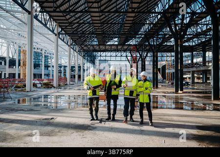Team of engineers and construction workers inspecting building progress. Stock Photo