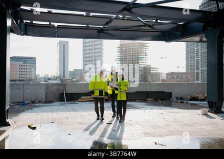 Team of engineers and construction workers inspecting building progress. Stock Photo