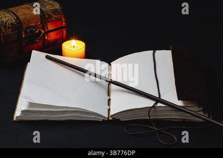 Image of open magic book and wand on the table in the dark room Stock Photo