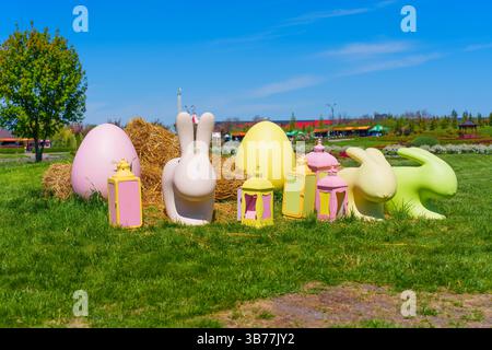 Pastel-colored Easter bunnies and eggs arranged on green grass, set against a clear blue sky, ideal for festive themes. Stock Photo