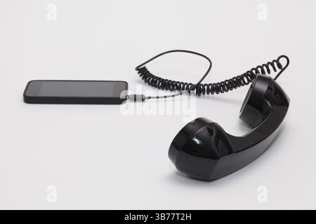 Old phone reciever and cord connection with new phone. Funny hotline concept Stock Photo
