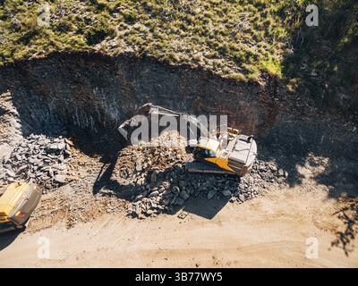 Yellow tracked tractor is working on the extraction of rock. View from above. Stock Photo