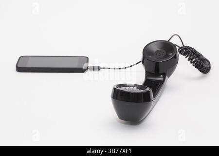 Old phone reciever and cord connection with new phone. Funny hotline concept Stock Photo