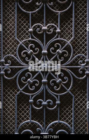 Metal forging on door, blue, against the background of small mesh of slave. Elements of architectural decoration of ancient buildings - old metal forg Stock Photo