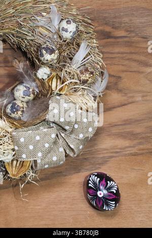 Easter wreath with dry grass, pine cones, feathers, quail and Easter eggs on the wooden table Stock Photo