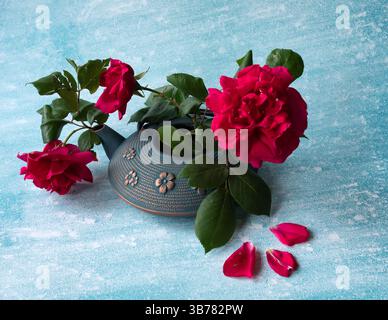 top view of a iron kettle with red roses and a teacup on the blue background. Selective focus, copy space. Traditional Asian tea ceremony arrangement Stock Photo