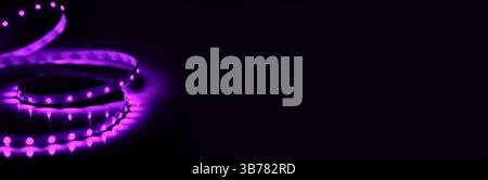Led strip coil. Shining violet diodes on black background empty copy space horizontal banner. Stock Photo