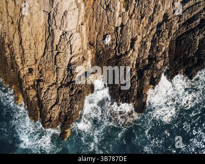 Man and woman in love lying embracing and on the rocky seashore, top view . Stock Photo