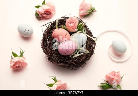 Easter eggs in nest closeup decorated with flowers on pink backgrund.Beautiful spring holiday composition. Stock Photo