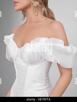 Blonde woman in elegant wedding dress poses gracefully in bright interior setting Stock Photo