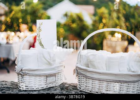 Blank card with ornament stands on rolled towel in white wicker basket on table. Wide angle. Stock Photo