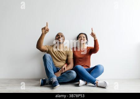 Happy Young Black Couple Pointing Up At Copy Space Above Their Heads Stock Photo