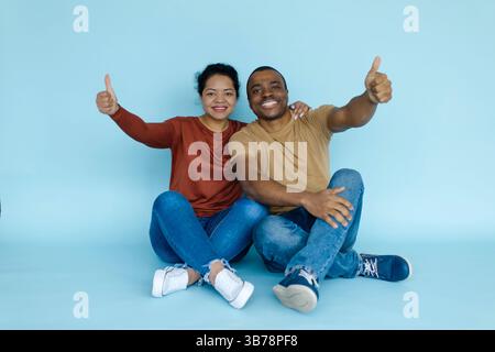 Best Choice. Portrait of happy black couple gesturing thumbs up at camera Stock Photo