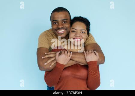 Smiling African American couple embracing against light blue background Stock Photo