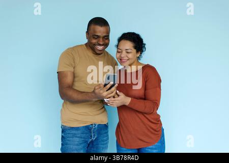 Cool App. Excited black couple looking at smartphone screen in hands Stock Photo