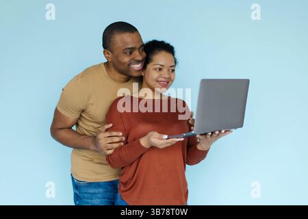 Young african american couple using laptop on blue background in studio Stock Photo