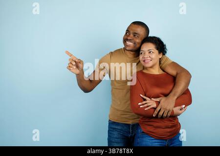 Look There. Young Black Couple Pointing Aside At Copy Space Stock Photo