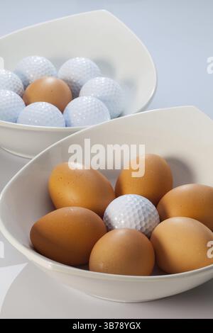 Two white ceramics bowls, easter eggs and golf balls Stock Photo